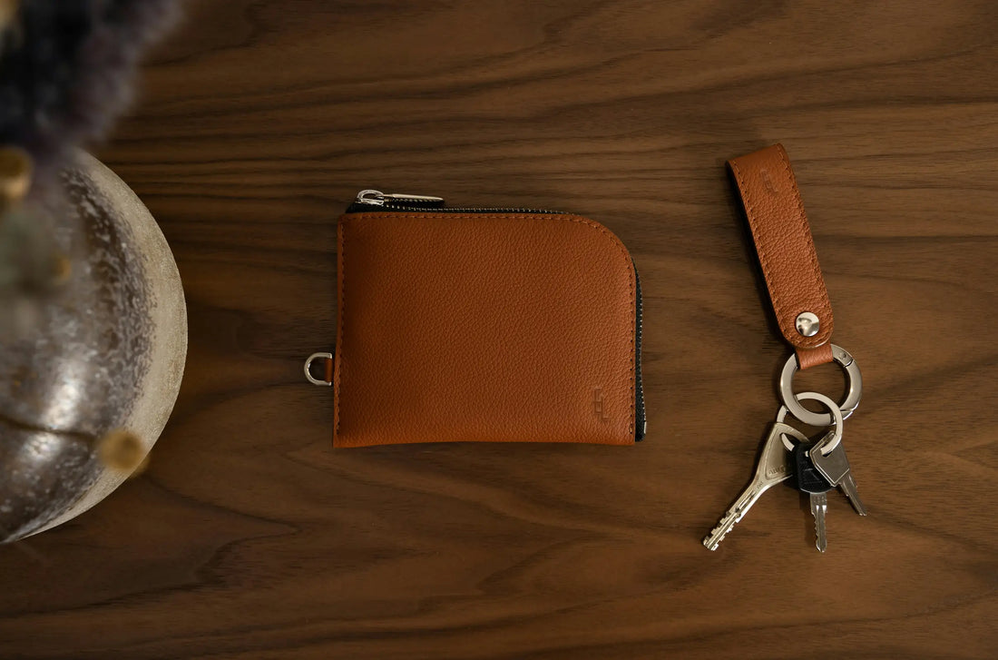 Premium brown leather wallet with zipper and matching keychain on wood table, by EligoLeather.