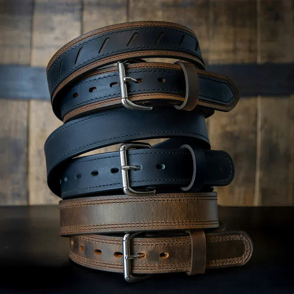 Stack of black and brown leather belts with silver buckles on wood background, stylish and durable.